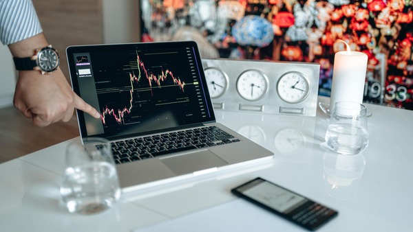 Laptop showing a cryptocurrency price chart next to a smartphone on a desk, representing wallet comparison across devices