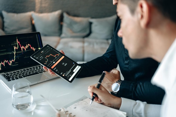 Traders reviewing a cryptocurrency exchange rate chart on a laptop and phone